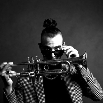 Tomcat Trumpet with his trumpet in a monochrome editorial portrait